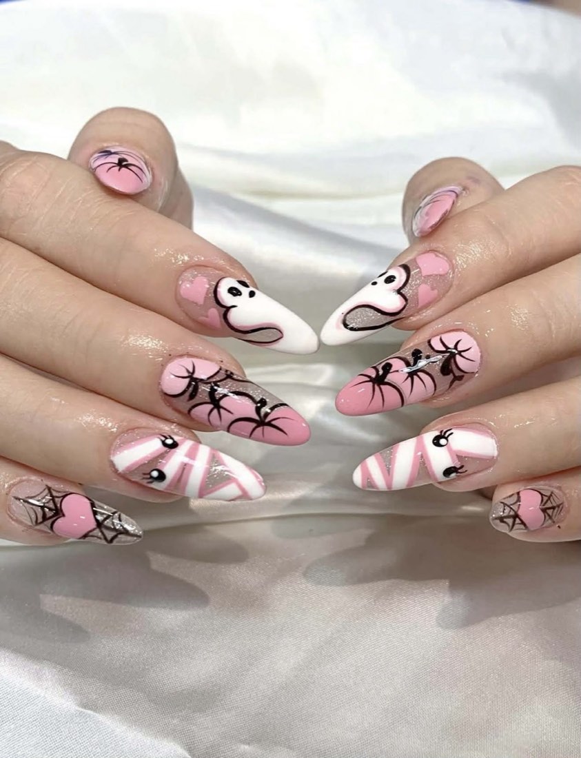 Pink hand-painted nail art with cartoon and web designs on almond nails
