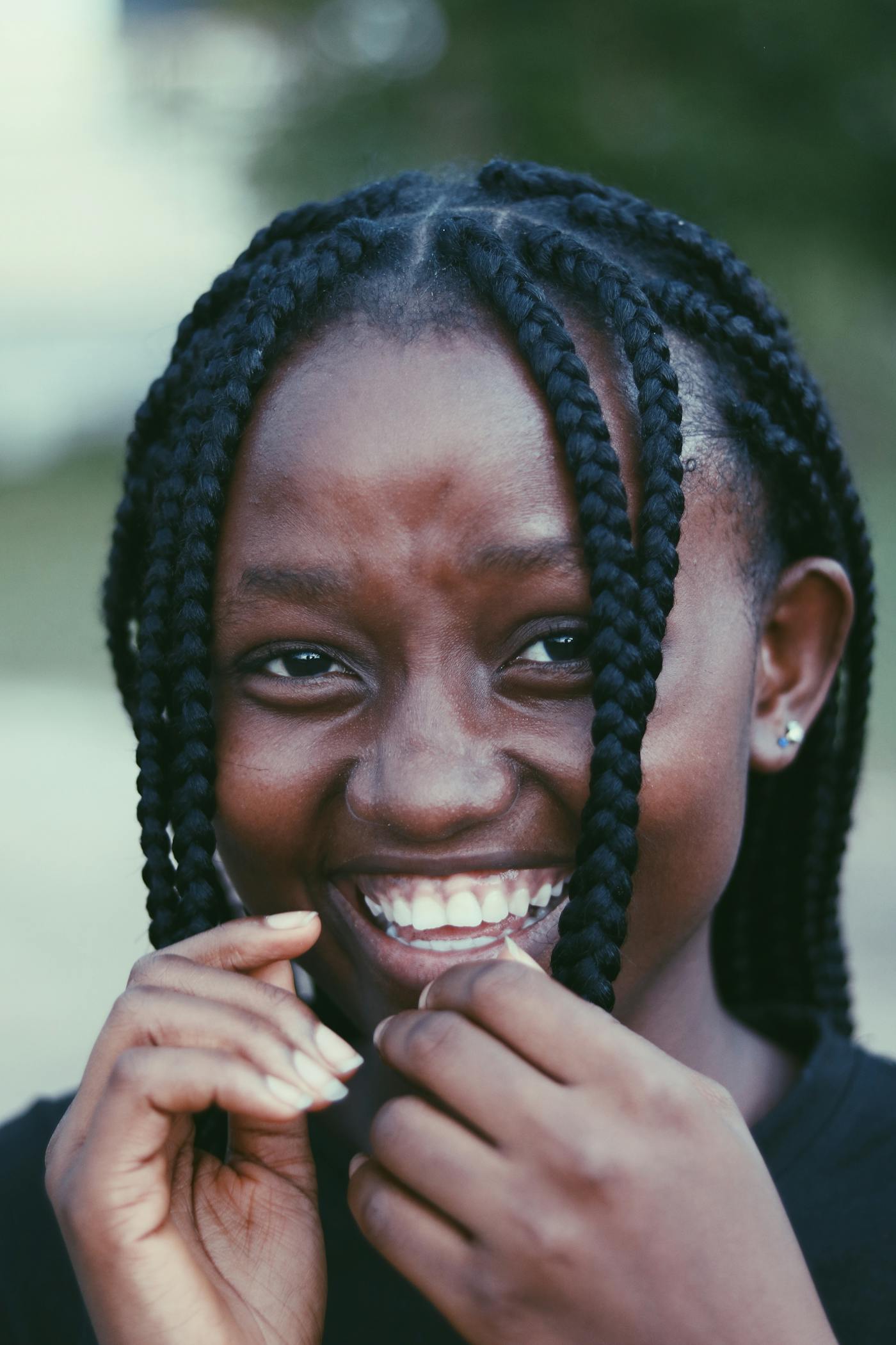 Box braids worn half-up, joyful smile