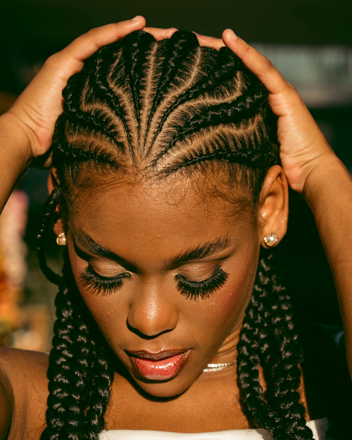 Feed-in cornrow braids with razor-clean parts, framed by hands