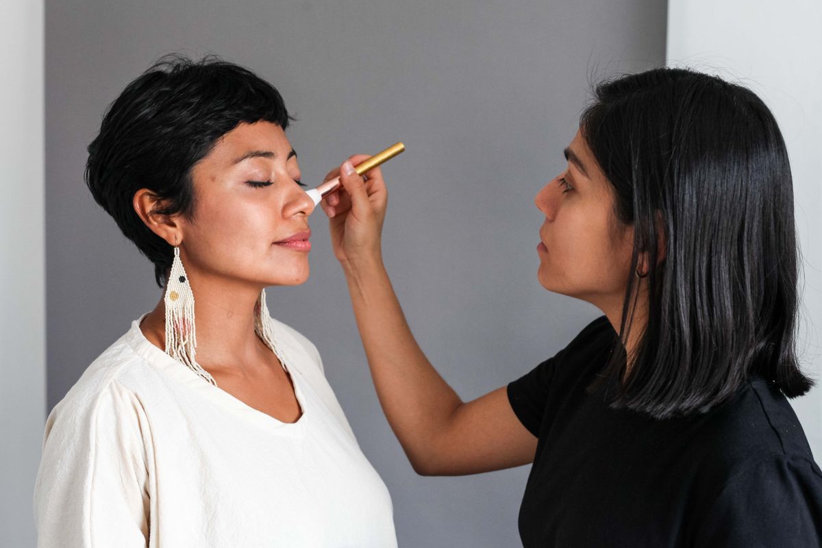 A makeup artist applying soft natural glam to a client in the studio — representative of the work