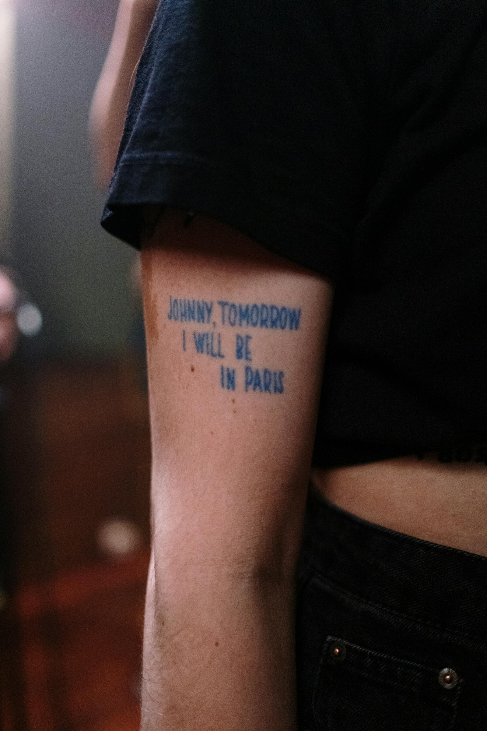 Multi-line custom quote lettering tattoo on a forearm