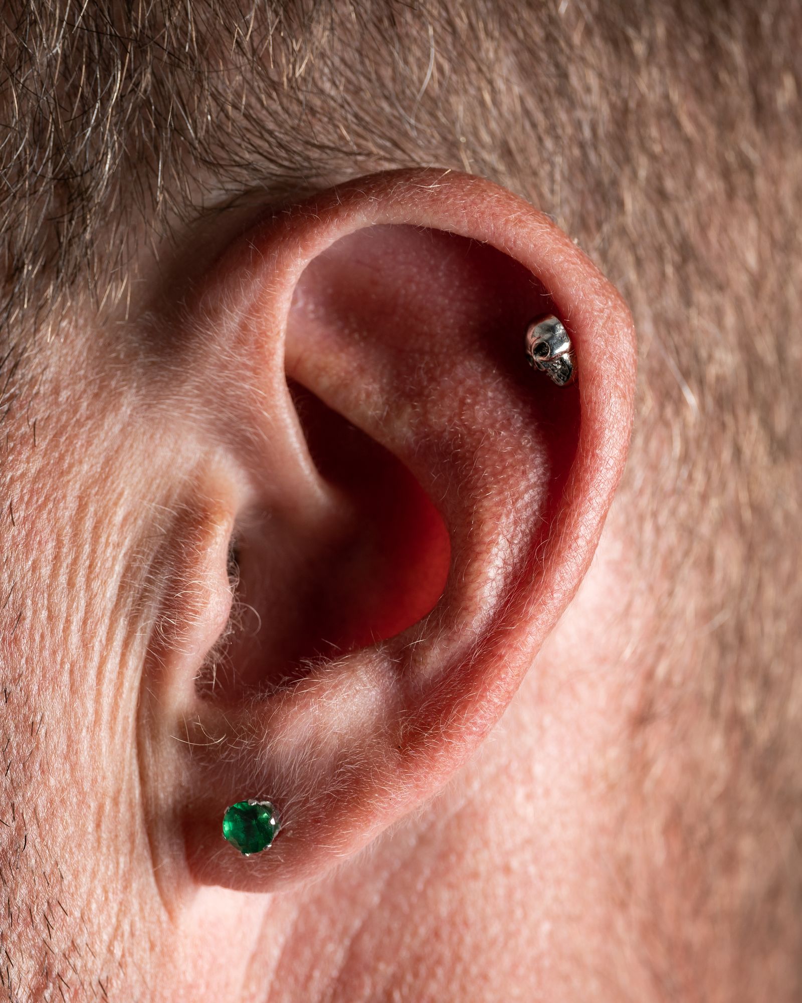 Close-up of ear piercings with an emerald stud