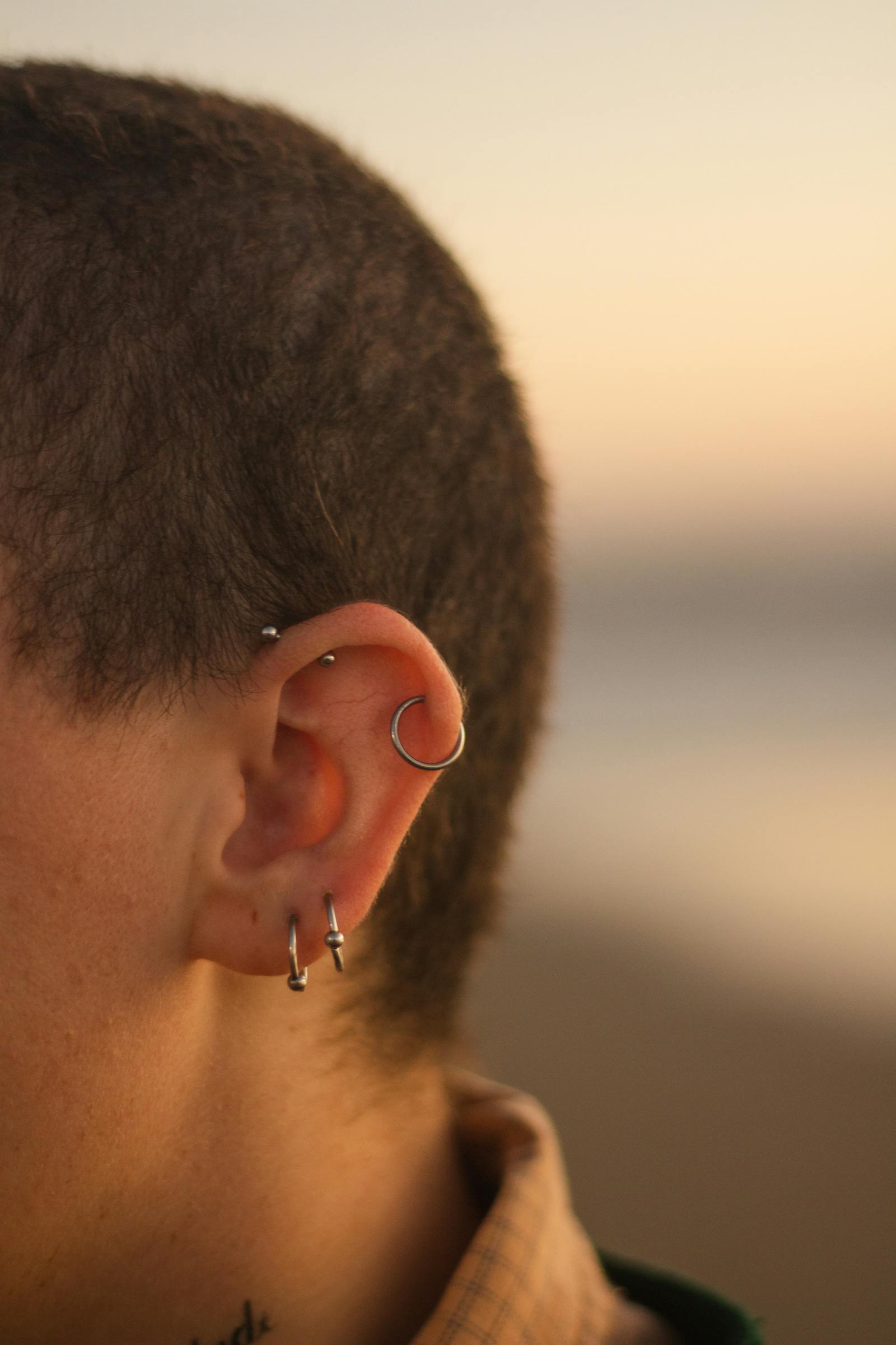 Multiple ear piercings with hoops in warm light