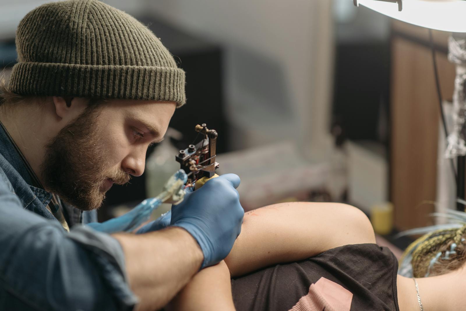 A tattoo artist working with a machine, focused mid-session