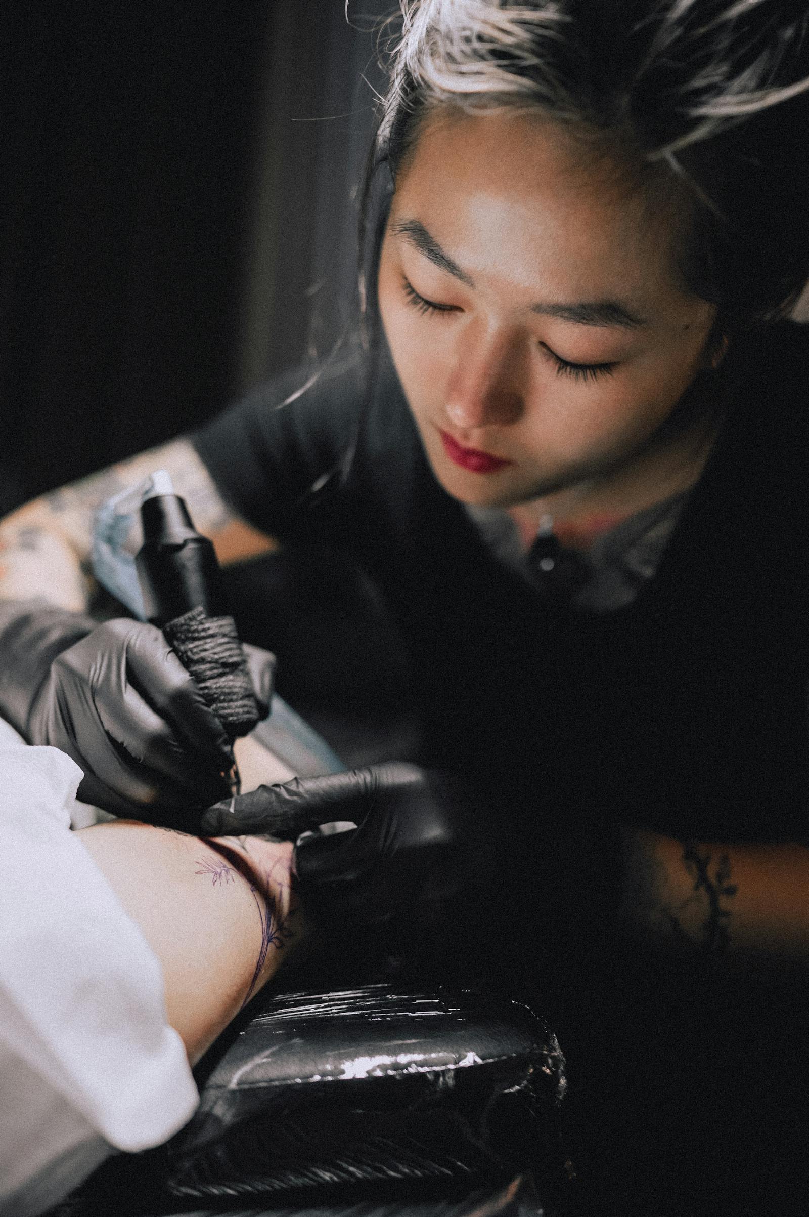 An artist tattooing a fine-line design